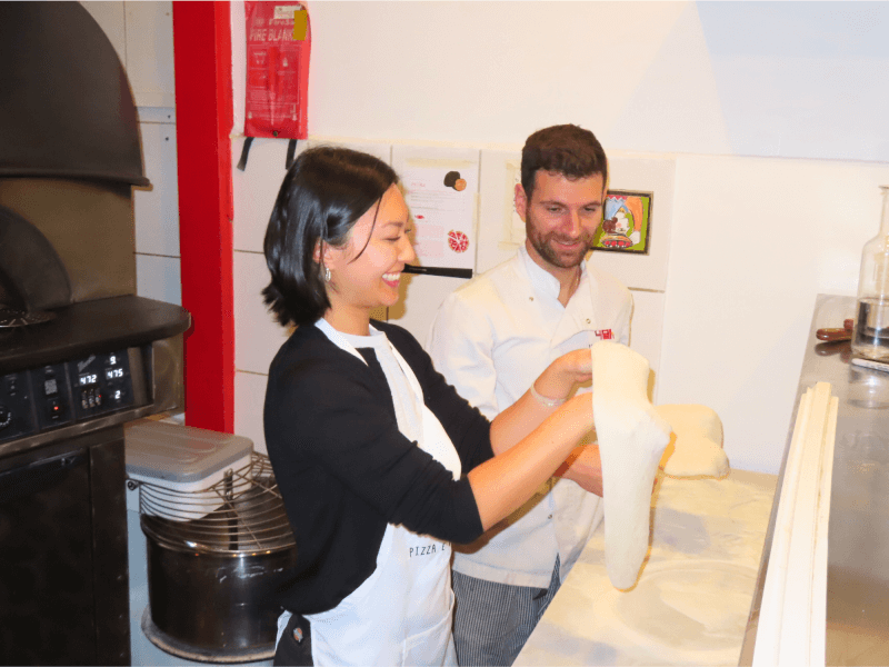 Teacher with student making pizza
